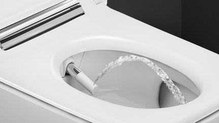 Ein modernes Bidet mit einem Wasserstrahl, der aus der Düse in die Toilettenschüssel spritzt, auf einem weißen Hintergrund.