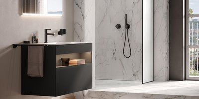 Ein modernes Badezimmer mit einem eleganten schwarzen Waschbecken und einem großen Spiegel, der sanft beleuchtet ist.