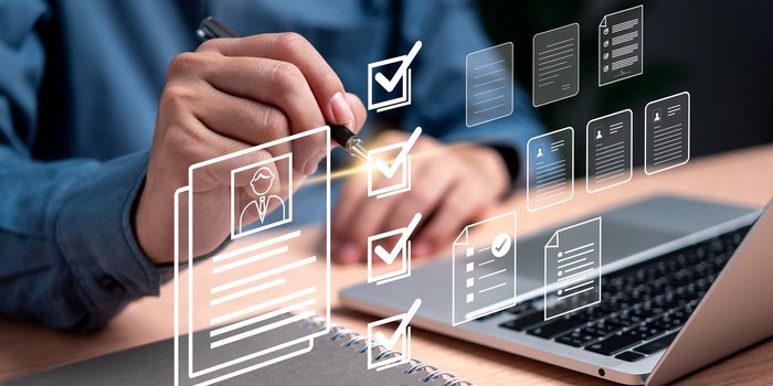 Ein Laptop und ein Bewerbungs header mit einer Männerhand die ein Kugelschreiber hält